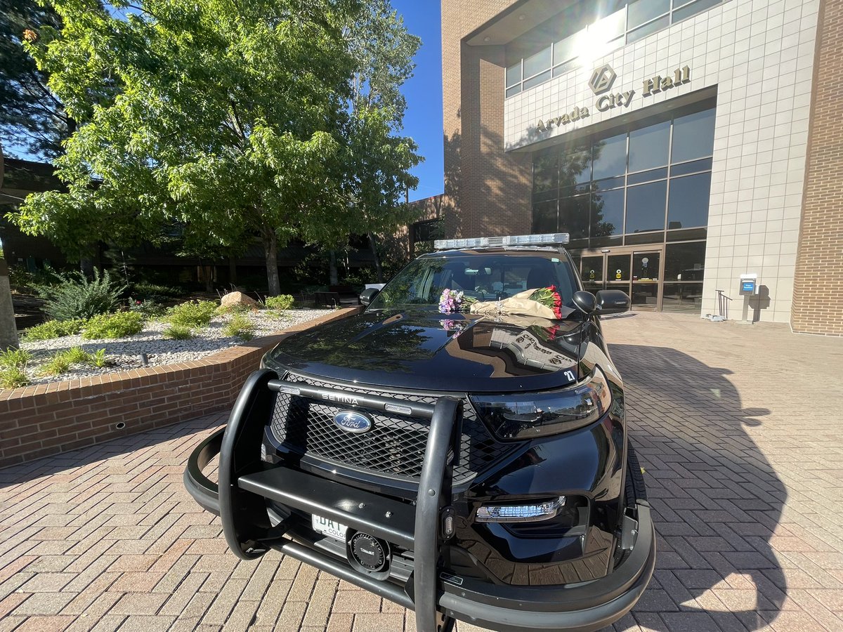 An Arvada officer was killed while responding to a disturbance. A suspect is in custody.   Flowers sit on an Arvada cruiser outside the police station