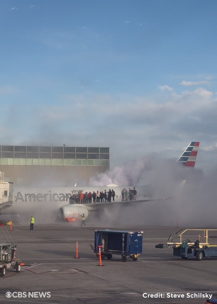 An American Airlines plane carrying 178 people appeared to catch fire on the tarmac after making an emergency landing at Denver International Airport , forcing passengers to evacuate by climbing out onto the wing of the plane